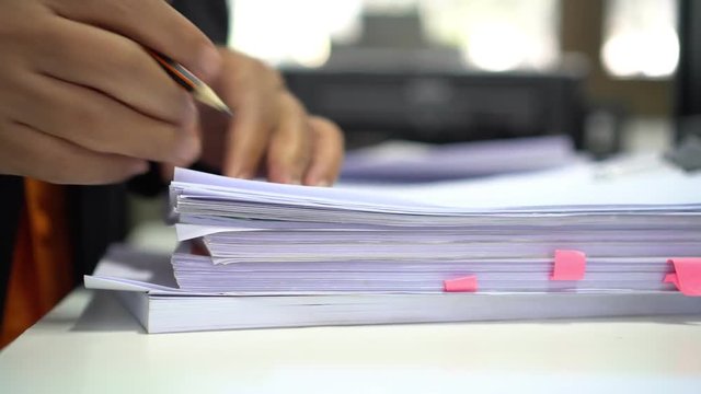 Businessman signing in report paperwork of stacks paper files and searching unfinished document achieves on busy work desk office. 4k