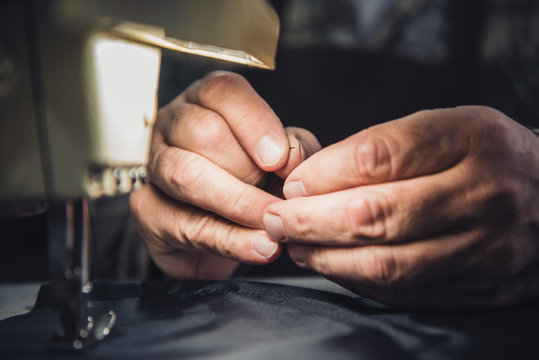 cropped image of male handbag craftsman sewing at studio