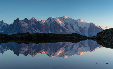 Panorama of the Mont Blanc massif reflected in Lac de Chesery during blue hour. Chamonix, France.