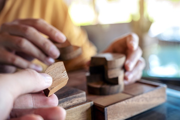 Fototapeta na wymiar Closeup image of two people playing and building round wooden puzzle game