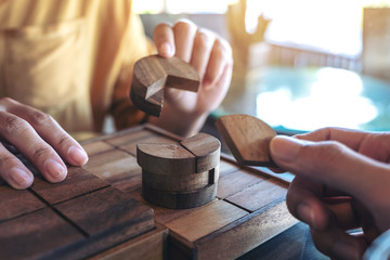 Closeup image of two people playing and building round wooden puzzle game