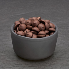 Chocolate chip  morsels or drops in cup top view isolated on dark or black background