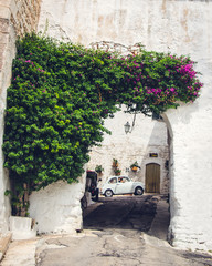 The traditional italian summer view of old street with white Fiat 500