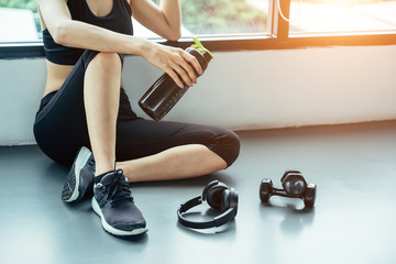 Asian woman exercising in the gym, Young woman workout in fitness for her healthy and office girl lifestyle. She using smart phone to check an email or listening music.