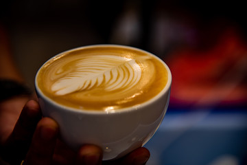 Closeup hand of barista making art for latte, cappuccino coffee pouring milk making to offer customers a taste of the coffee drink.