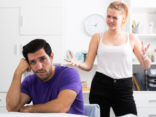 Upset man at table with disgruntled woman behind