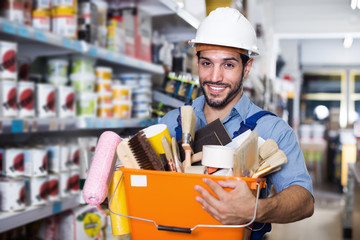 Handyman holding basket with tools in paint shop