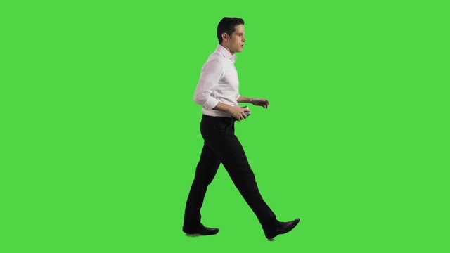 Very nervous businessman late for something, annoyed, walking very fast sideways over a greenscreen. Two takes.