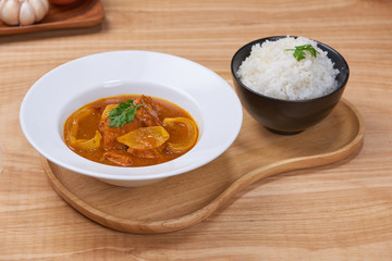 Tasty dinner with chicken curry in bowl on wooden background