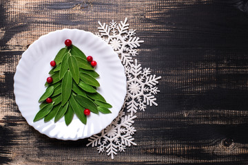 Green Christmas tree lined from sage leaves on a plate, on wooden vintage background
