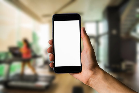 Hand holding white mobile phone with blank white screen  in Exercise room.