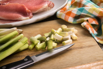 organic spring onion and raw bacon on a wooden board
