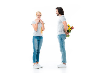 Fototapeta premium shocked girl and man hiding bouquet of flowers isolated on white