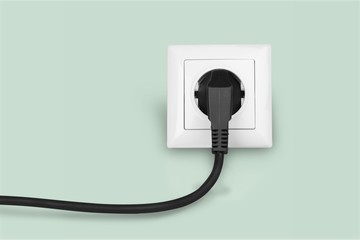 White electrical plug in the electric socket on a wall - obrazy, fototapety, plakaty