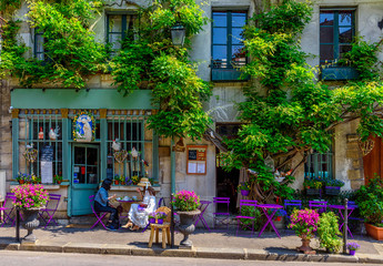 Cozy street with flowers and tables of cafe  in Paris, France
