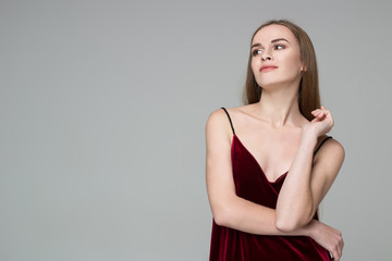 Fototapeta premium Young blond girl in dark red dress showing emotions: satisfaction