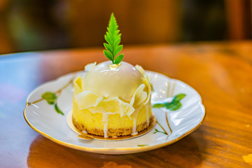 White chocolate assorted with berry cake served in a white plate on the luxury table cloth and wooden table. Selective focus with blurred background