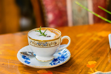 Hot cappuccino in white ceramic cup on the  wooden table, top view