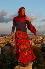 A woman in red long skirt and scarf at sunset in Istanbul
