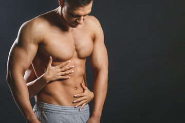 Fototapeta premium Love and sex concept - female hands touching muscular man isolated over grey background. Sexy fit couple, posing on a dark blackground.