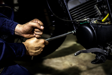 Obraz premium People use hand are repairing a motorcycle Use a wrench to work. Use the wrench to tighten the cylinder.