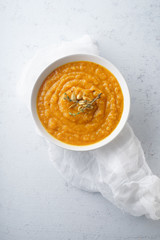 Pureed pumpkin soup with seeds and thyme. Warm food concept, dieting. Concrete background, overhead view.