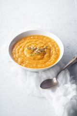 Pureed butternut squash soup with seeds and thyme. Warm food concept, dieting. Concrete background, side view.