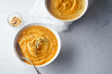Pureed pumpkin soup with seeds and thyme. Warm food concept, dieting. Concrete background, overhead view. Copy space