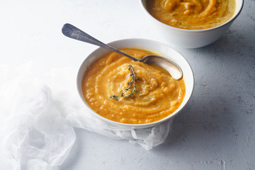 Pureed butternut squash soup with seeds and thyme. Warm food concept, dieting. Concrete background, side view.