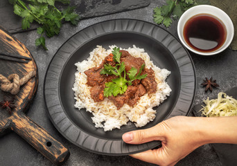 hand puts a plate of Asian food on the table