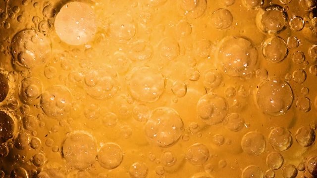 The golden bubbles move in the fluid. The chemical process with dissolution in liquid. Abstract background from yellow air bubbles.