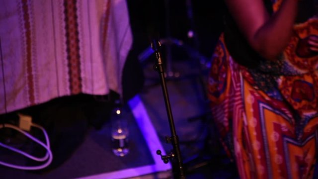 Female rapper preforms on stage in ankara dungarees
