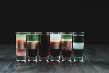 Small glasses drink shots of alcohol in a wooden black table 
