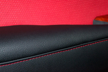 Interior of the SUV car with a rebuilt leather in red-black color in exchange for the old worn-out interior trim in the workshop for repairing the seat panels and steering wheels