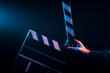 Opened clapperboard for cinema in hand, before filming on a black isolated background with red and...