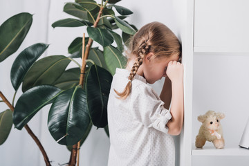 side view of little child standing behind bookshelves