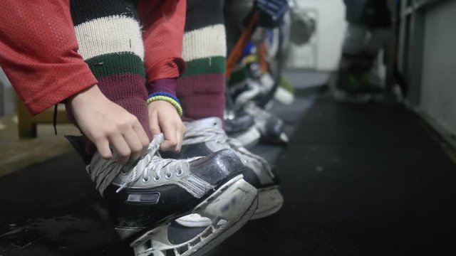 hockey player tying shoelace on skating and ready to go on rink, close-up on unfocused background