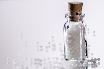 white homepathic globules in a small bottle of glas
