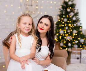 portrait of woman with cute little girl in decorated living room with Christmas tree and gifts