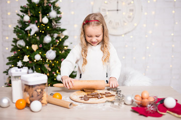 Obraz na płótnie Canvas portrait of cute girl baking Christmas cookies in kitchen with Christmas tree