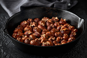 Roasted chestnuts served in cast iron vintage pan.
