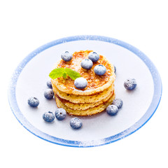 Pile of pancakes with blueberries sprinkled with icing sugar