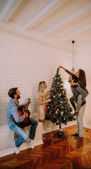 Couples hanging christmas decorations on the tree