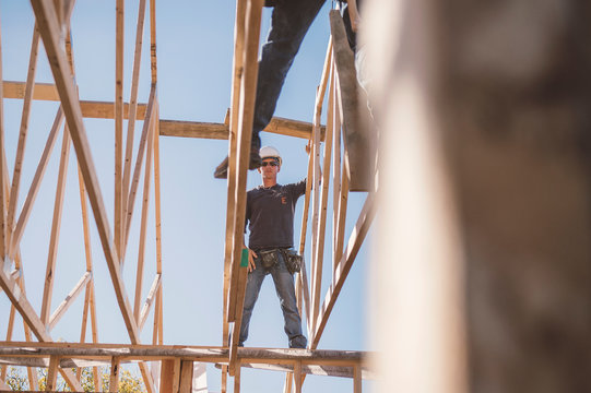 Builders working on rooftop frame of building