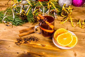 Cup of mulled wine with cinnamon, christmas decorations, sliced orange and fir tree branches on...