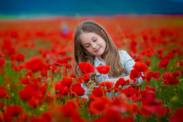 Beauty blue eyes teen enjoy summer days .Cute fancy dressed girl in poppy field. Field of blooming poppies.