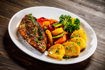 Grilled chicken fillet and vegetables on woowde table