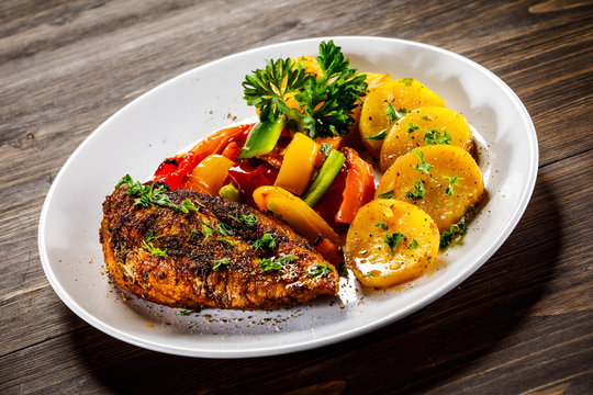Grilled chicken fillet and vegetables on woowde table