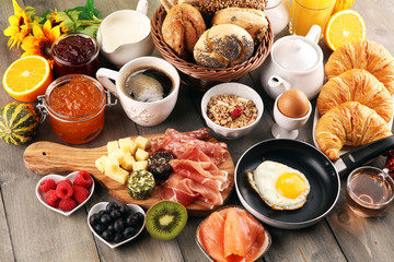 breakfast on table with bread buns, croissants, coffe and juice.