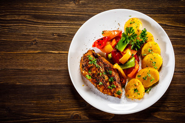 Grilled chicken fillet and vegetables on woowde table